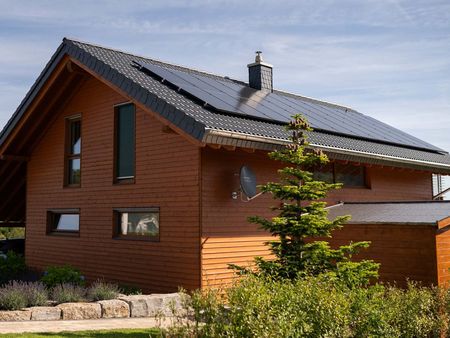 Haus aus Holz mit Photovoltaikanlage auf dem Dach