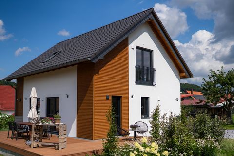 Terrasse mit Blick auf das Einfamilienhaus in Lichtenau Sonnige Terrassenseite des Einfamilienhauses in Lichtenau mit gemütlicher Sitzgruppe, Holzfassade in Rhombusprofil und weiß verputzter Hauswand